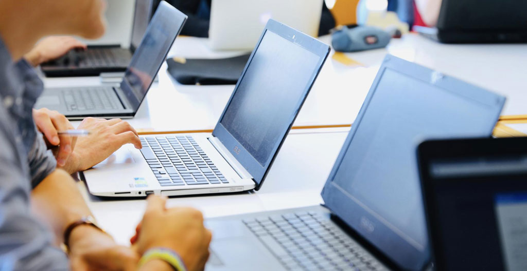 Illustration isométrique représentant quatre types d'acteurs ESN de tailles différentes, du gratte-ciel symbolisant une grande ESN au studio représentant un freelance, avec icônes de spécialités technologiques.